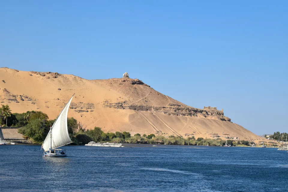 A white sail on the Nile with desert hills beyond