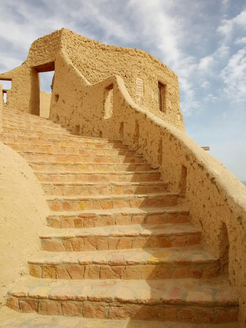 Sunlit stone steps and earthen buildings in Siwa