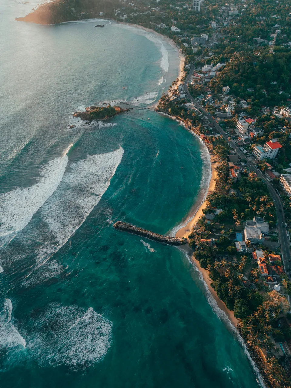 An aerial view of a curved beach beside a coastal town