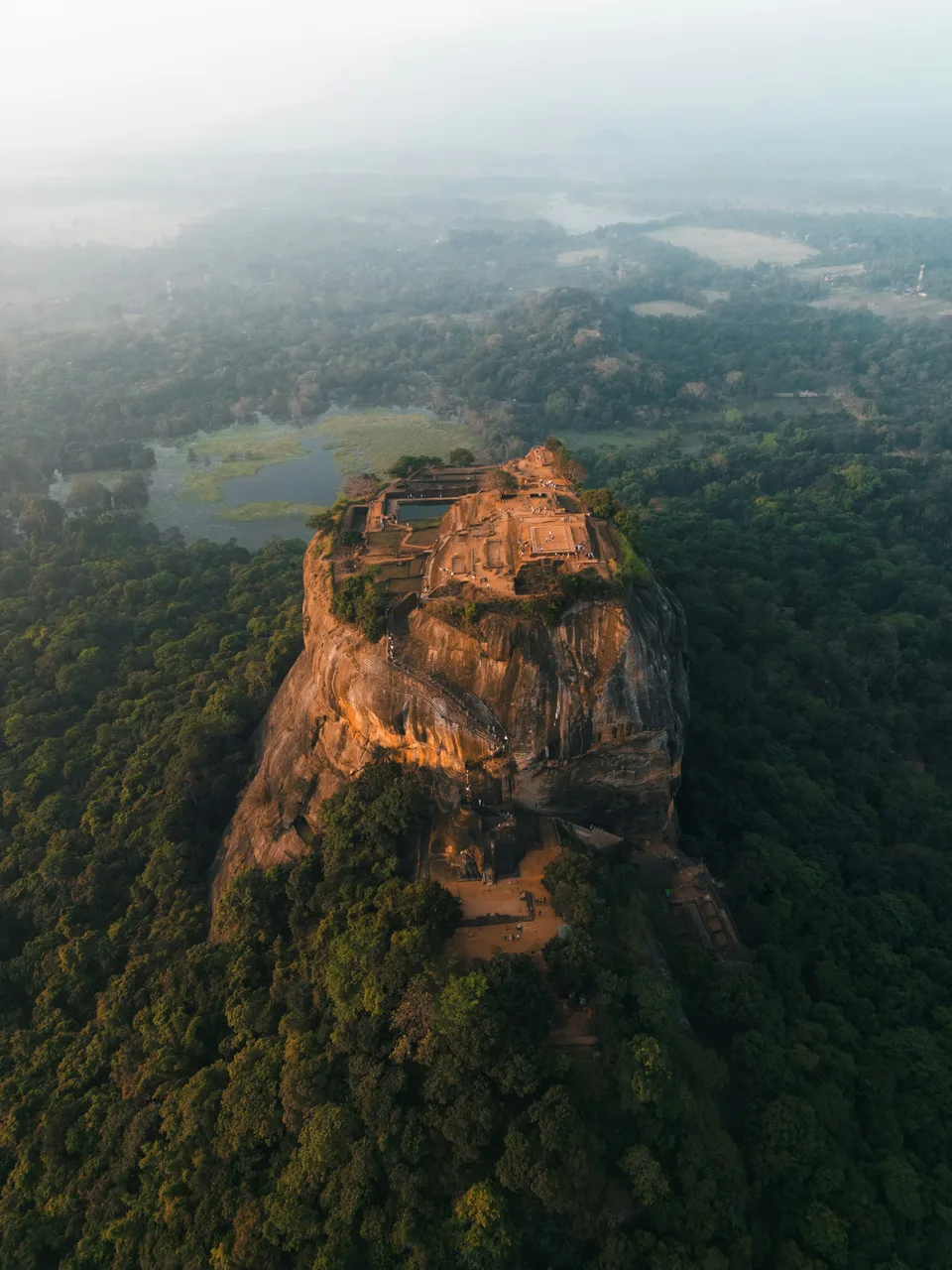 Sigiriya rock rising from misty forest