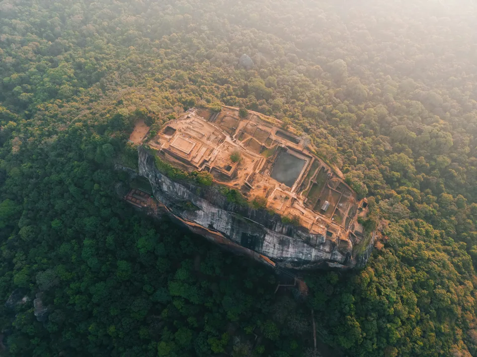 Aerial view of the stone ruins atop Sigiriya rock surrounded by forest