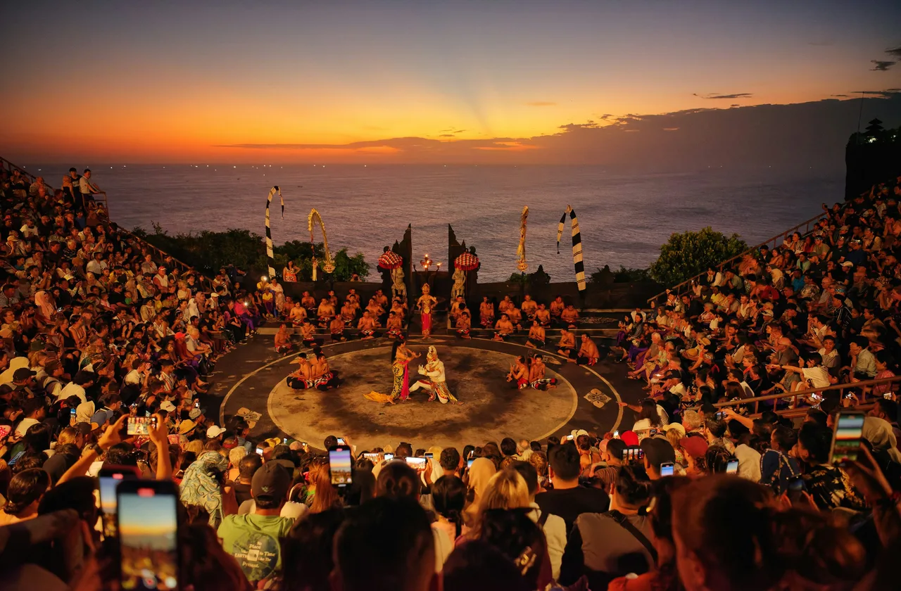 A circular Kecak performance with an ocean sunset behind it