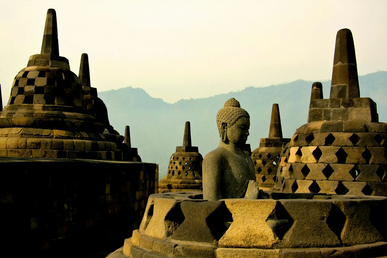 Stone stupas and a Buddha statue at Borobudur in the morning light