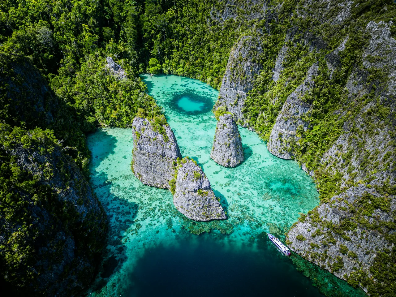 Clear water between forested limestone cliffs in Raja Ampat