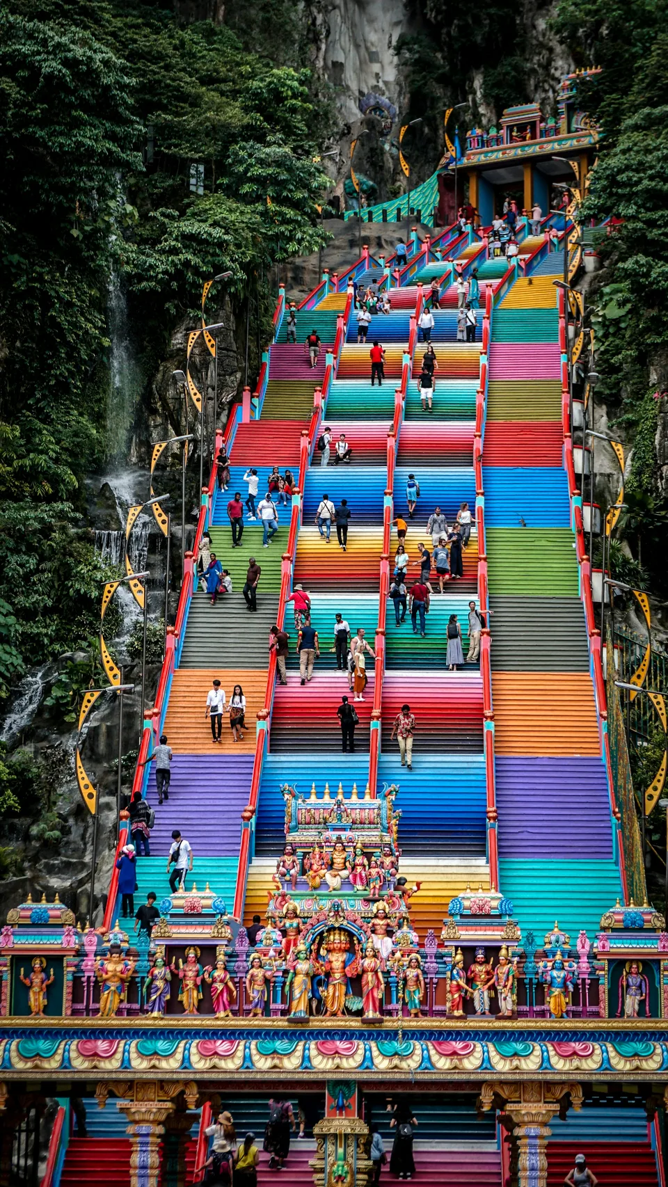 Rainbow-coloured stairs climbing between green limestone cliffs