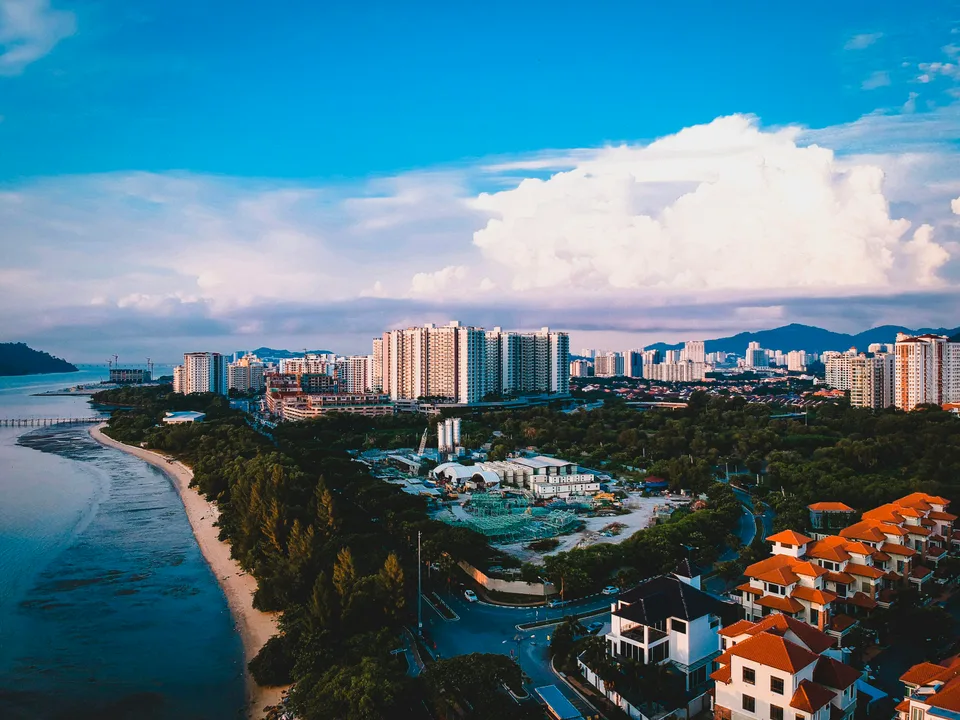 Long sandy coastline curving around Penang buildings and hills