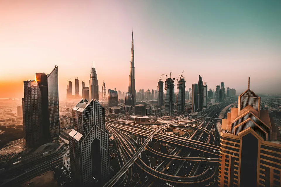 Dubai skyline and Burj Khalifa above sweeping highway interchanges at sunset
